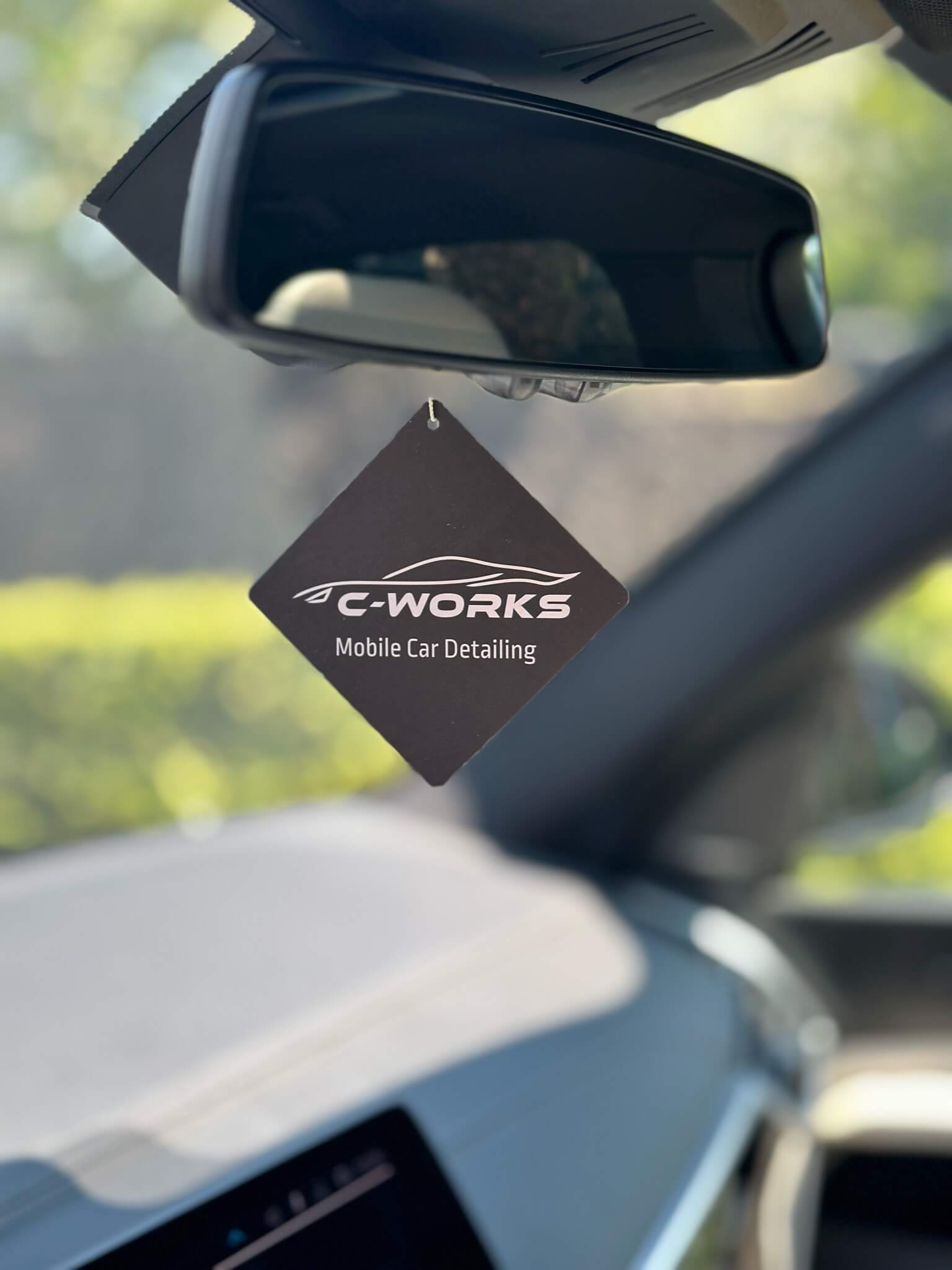 een close up van een geurhanger van C-Works Car Detailing die in een auto hangt
